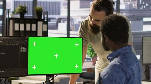 System administrator does software debugging on green screen PC with colleague Stock Photos