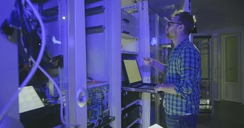 System administrator in glasses checks server functions looks at computer screen Stock Footage 107341039