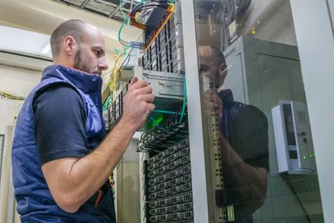 System administrator installs a new server in a modern data center. A man wor Stock Photos