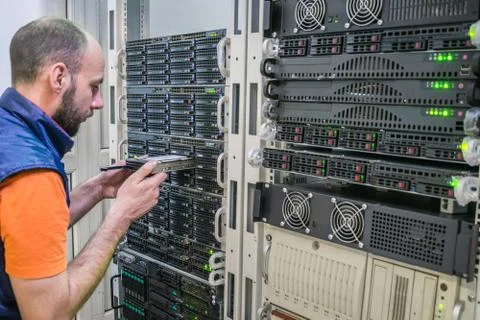 The system administrator replaces the data disk. A man works in the server ro 库存照片