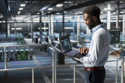 System administrator in server hub using laptop for neural network overseeing Foto stock