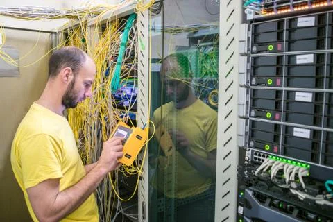 The system administrator is testing the network with a reflectometer. The man Stock Photos