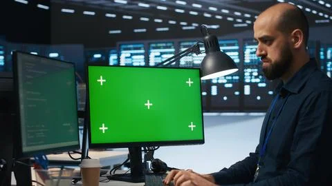 System administrator working on green screen computers in data center Stock Photos