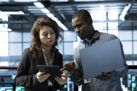 System administrators in data center using devices, executing security patches Foto stock