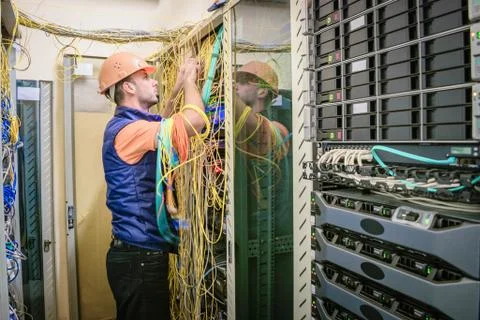 A system engineer commutes many messy wires in the server room.  Restoration  库存照片