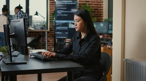System engineer focused on writing code sitting at desk in software development Stock Photos