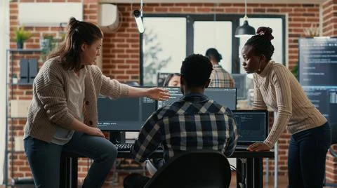 System engineer sitting on desk discussing with mixed team of coders about ai 스톡 사진
