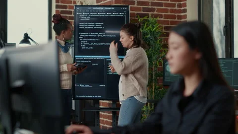 System engineers comparing source code on wall screen tv analyzing errors using Stock Footage 168235914