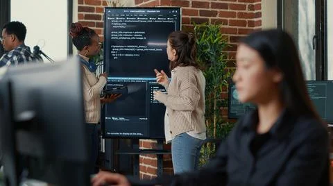 System engineers comparing source code on wall screen tv analyzing errors using Foto stock