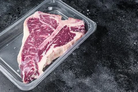 T-bon raw beef steak in vacuum packaging. Black background. Top view. Copy space Stock Photos
