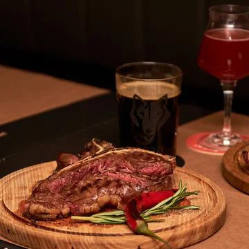 T bone Beef Grilled steak meat with rosemary branch, pepper, salt and glass o Stock Photos
