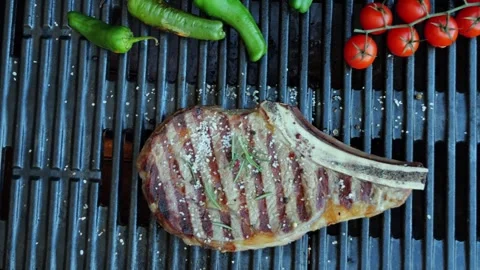 T bone beef steak on barbecue grill grate, flame. Top view. Close up. Stock Footage 256041794