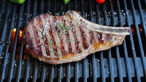 T bone beef steak on barbecue grill grate, flame. Top view. Vegetables Stock Footage 256809254