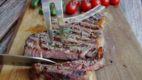 T bone beef steak on board cut with a knife. Close up. Slow motion Vídeos de archivo 255978564