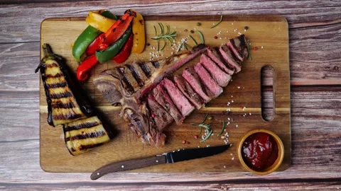 T- bone beef steak grilled sliced with grilled vegetables wooden board. Top view Video stock 272151112