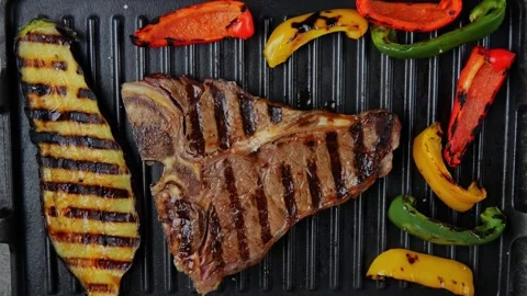 T- bone beef steak turn over on grill, grilled vegetables. Slow motion. Top view Video stock 266126381