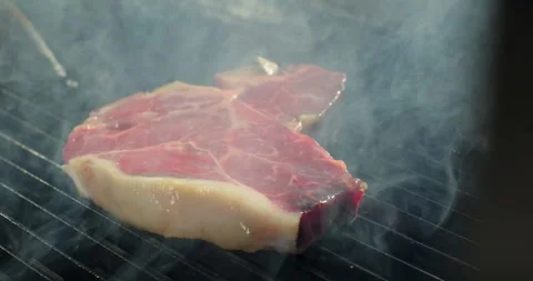 T-bone meat steak on barbecue charcoal grill. Grilling BBQ meat. Smoke rising Stock Footage 269834289