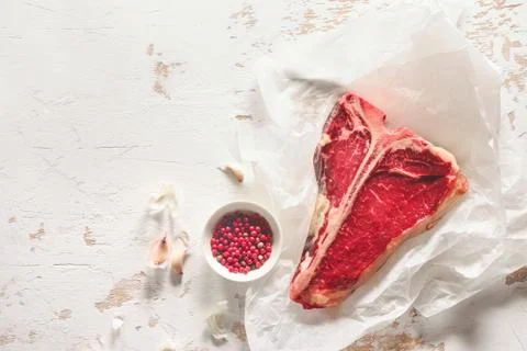 T-bone raw steak on a kitchen table surface, view from above Stock Photos