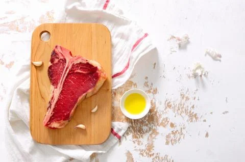 T-bone raw steak on a kitchen table surface, view from above Stock Photos