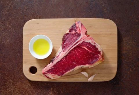 T-bone raw steak on a kitchen table surface, view from above Stock Photos