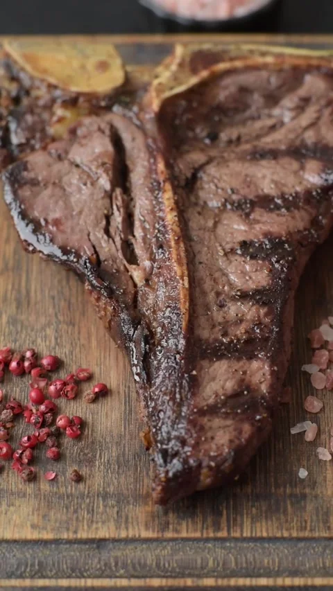 T-bone steak, beef meat grilled until done rare with salt and spices. T-bone ste Stock Footage 339784737