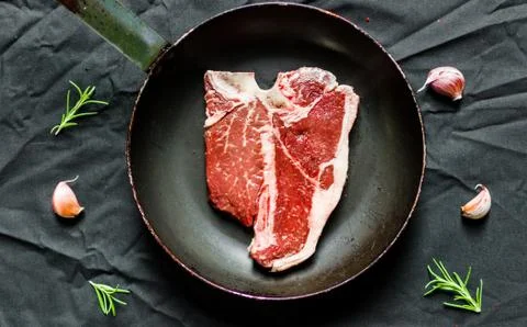 T bone steak of beef meat against black background Stock Photos