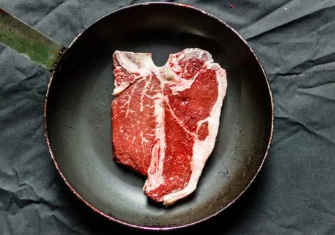 T bone steak of beef meat against black background Stock Photos