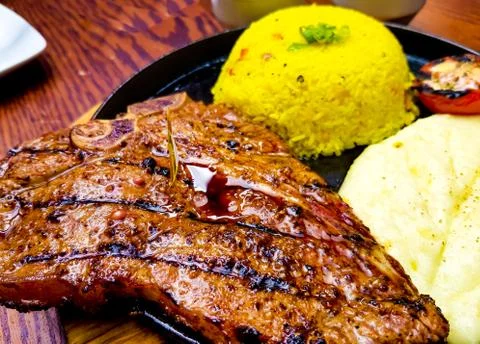 T-bone steak cooked medium rare with mashed potato and saffron rice decorated Foto stock