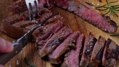 T- bone steak cut into pieces with a knife on a cutting board. Close up Stock Footage 265460201