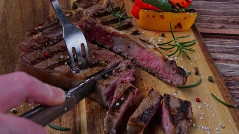 T- bone steak grill cut into pieces with  knife on  cutting board. Close up Stock Footage 265460254