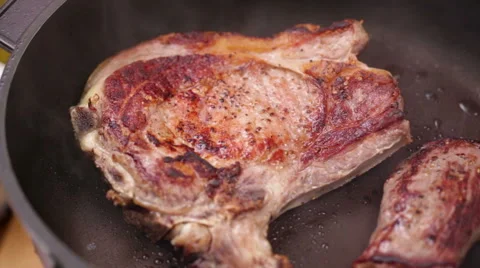 T-bone steak grilling in non stick frying pan Stock Footage 44633824