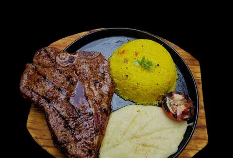 T-bone steak with mashed potato and saffron rice with black background Stock Photos