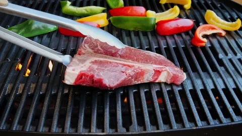 T- bone steak put on cast iron grill barbecue. Slow motion Stock Footage 265460236