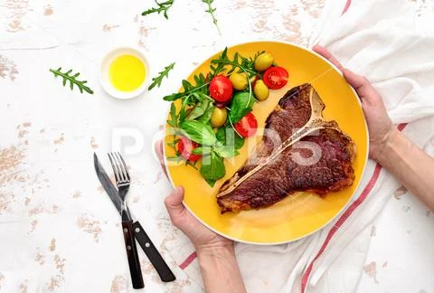 T-bone steak ready to eat, served on a plate, view from above Stock Photos