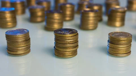 A table with 3 stacks of gold coins that increase and then decrease. Money Stock Footage 269897164