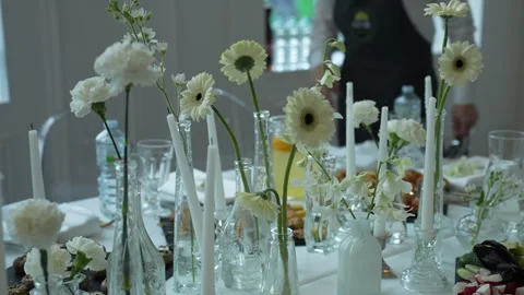 A table adorned with white flowers in vases and candles Vidéo 267867099