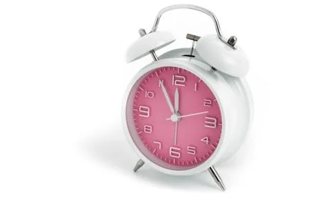 Table alarm clock with time 5 to 12 with pink clock face, 11.55 AM PM, on whi Stock Photos