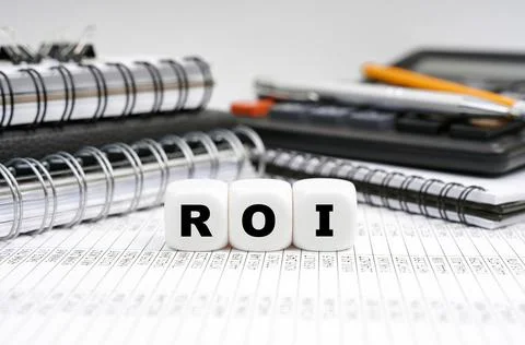 On the table, among office objects, cubes with the inscription - ROI Stock Photos