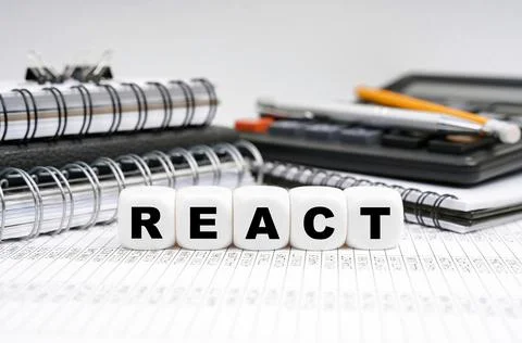 On the table, among office objects, cubes with the inscription - REACT Stock-Fotos