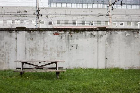 Table and bench in the grass with a wall Stock Photos