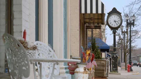 Table and chairs in front of shops on a street in a small town. 4k60p Stock Footage 128850306