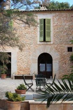 Table and chairs in front of a stone building Stock Photos