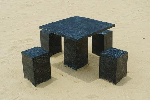 A table and chairs made of stone stands on the sand Stock Photos