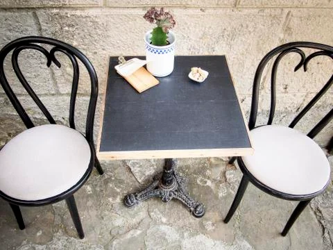 Table and chairs over wall of old building in the street cafe Foto stock