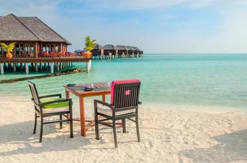 Table and chairs at restaurant at the background of water bungalows, Maldives Stock Photos