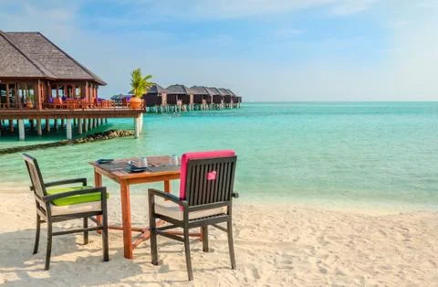 Table and chairs at restaurant at the background of water bungalows, Maldives Stock Photos