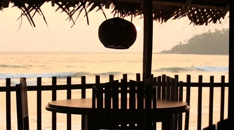Table and lamp in a tropical cafe on the beach at sunset Stock Footage 64768108