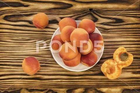 On the table and on a white saucer lie ripe apricots Stock Photos