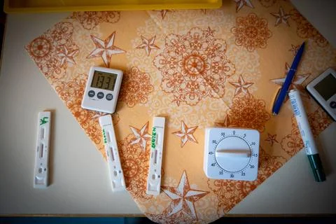 On the table are 3 Corona quick tests and next to them is a timer clock Stock Photos