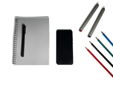 On a table are colored pencils and markers, a black smartphone, a white notebook Stock Photos